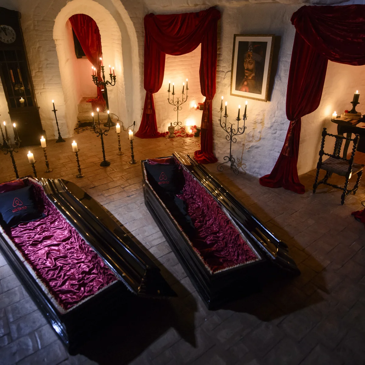 Încăpere luminată de lumânări, cu sicrie aranjate pentru un eveniment tematic Dracula la Castelul Bran